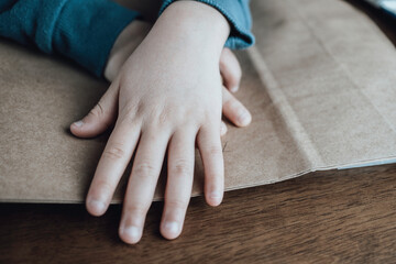 A child covering with his hands a paper with a message or drawing.