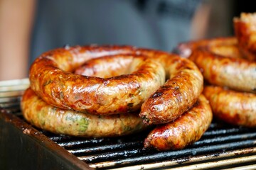 grilled Sai Aua (Northern Thai Spicy Sausage) on fire stove in morning light. street food.