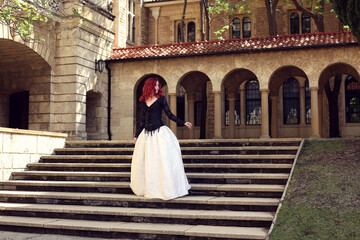Full length portrait of red-haired woman wearing a  beautiful gothic gown costume, walking around ...
