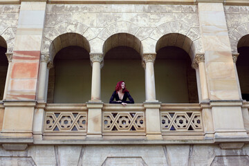 Full length portrait of red-haired woman wearing a  beautiful gothic gown costume, walking around  location with  romantic castle stone architecture background.