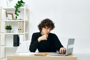 Naklejka premium curly guy on a white sofa in front of a laptop learning Lifestyle technology