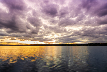 Fototapeta premium amazing scenic view at a twilight lake from a coast after dramatic colorful sunset with beautiful clouds and reflection on water surface
