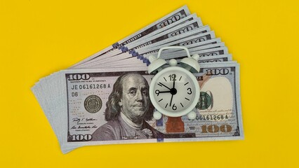 Top view of white alarm clock and bank notes. Copy space concept