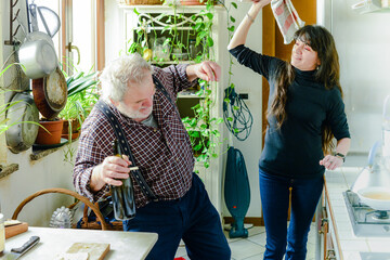 caucasian man drinking wine and getting drunk at home stressing  younger hispanic woman wife - alcoholism and domestic violence concept