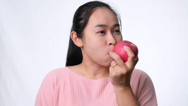 Asian woman holding an apple with a bite and smile showing strong teeth