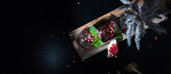 two colorful summer cocktails with pomegranate and mint on a black table