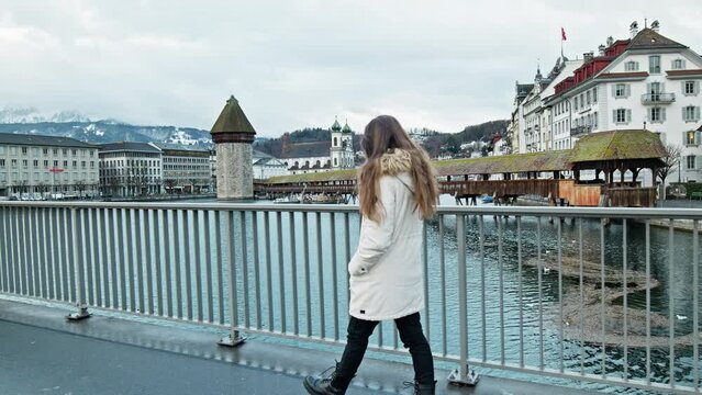 Tourist Girl looking at Chapel Bridge Kapellbrücke, Lucerne, Switzerland. A woman walking and exploring Swiss historical buildings and medieval architecture of an old city in Europe.
