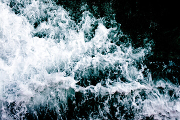 Top view of the ocean waves. Abstract blue ocean water with white foam background. Sea waves texture. Selective focus.