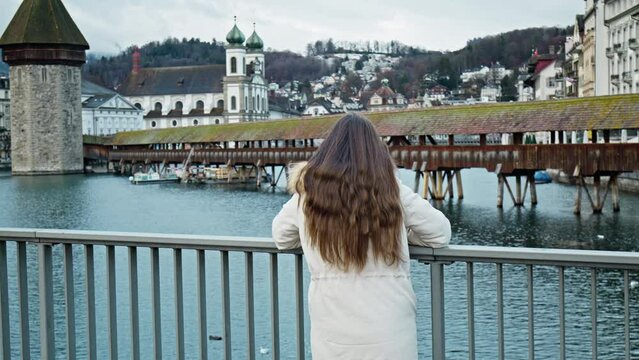 Tourist Girl looking at Chapel Bridge Kapellbr&uuml;cke, Lucerne, Switzerland. A woman walking and exploring Swiss historical buildings and medieval architecture of an old city in Europe.
