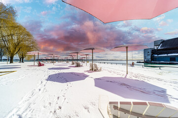 ugar Beach park down town Toronto with Pink Umbrellas Blue cloudy skies and snow on the ground and beach chairs