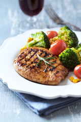 Grilled Turkey Breast with oven baked broccoli, cherry tomatoes and sweet corn. Close up.	