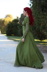 Full length portrait of red haired woman wearing a  beautiful  green medieval fantasy gown. Posing...