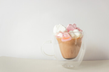 Glass double bottom cup of coffee with marshmallow in heart form. Isolated on white background.