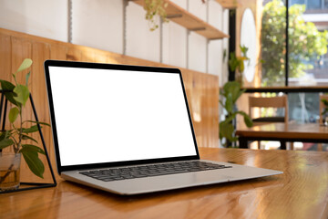 Fototapeta premium Computer laptop and potted plant on wooden table. Blank screen for advertise.