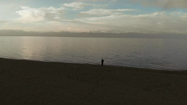 Aerial view of lonely old man standing on the sea shore