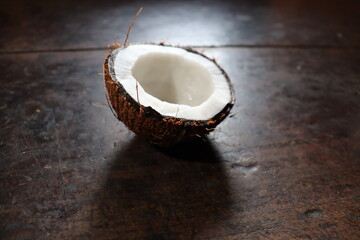closeup view of Indian coconut shell with white coconut inside which is cut into half piece with brown table background.