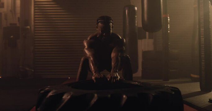 An African American Athlete Exercises, Tyre Pull In A Crossfit Gym. Shot In An MMA Boxing Gym With Low Key Lighting And A Scattering Of Haze. Captured On Red Digital Cinema Camera 