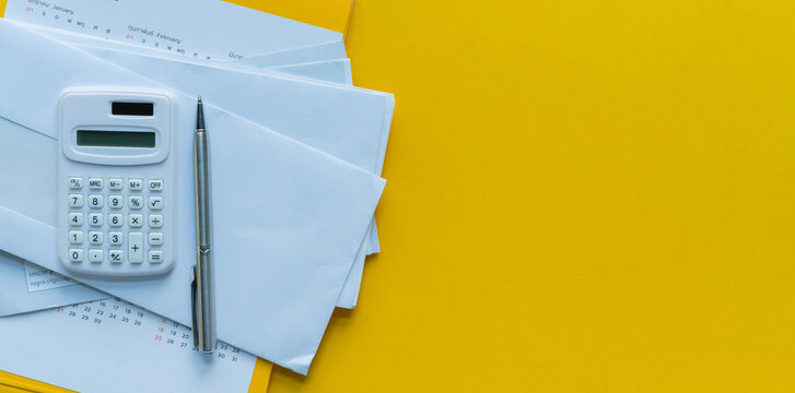 close up top view on calculator and open over group of invoice letter mail from bank on yellow background for money and debt management concept	