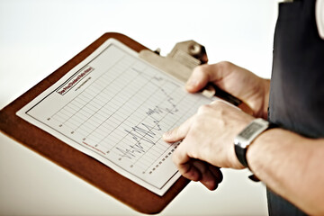 Fototapeta premium Long-term market tracking. A person pointing at a graph on a clipboard.