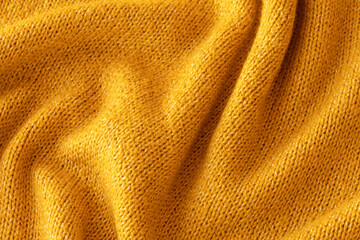 Soft knitted yellow sweater texture closeup. Light orange abstract background. Trendy soft mustard-colored backdrop for web design. Luxury twisted fabric backplate 