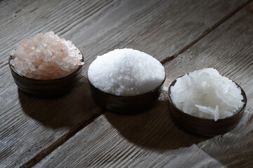 Different natural types of salt on a wooden background. Salt crystals in a wooden container