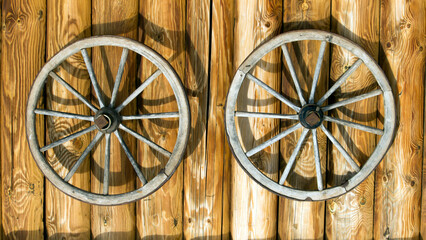 Obraz premium Two old wooden wheels on a log background, interior decor
