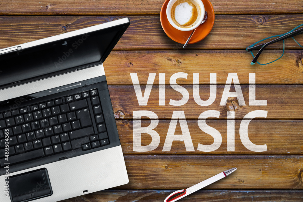 Poster visual basic programming language. word visual basic on wooden desk and laptop