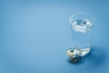 A glass of water and medicines on a blue background.