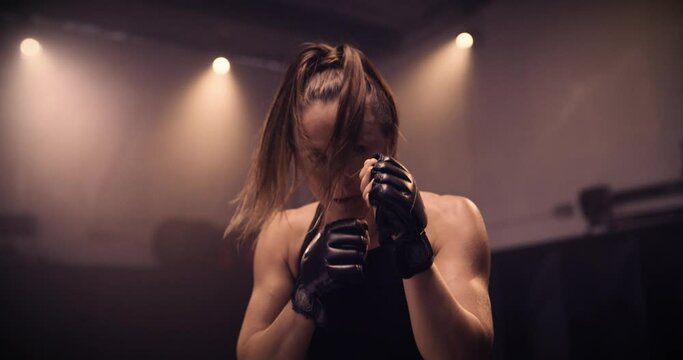 A POV Of A Strong Female Boxer Sparring / Punching Towards Camera. Shot In A Crossfit Boxing Gym With Low Key Lighting And A Scattering Of Haze. Captured On Red Digital Cinema Camera 