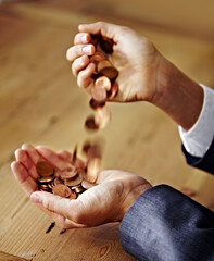 Playing with money. A closeup of hands pouring coins from one into the other.