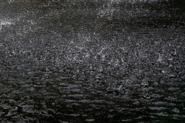 Fototapeta na wymiar Falling raindrops, splashing on water surface, close up view