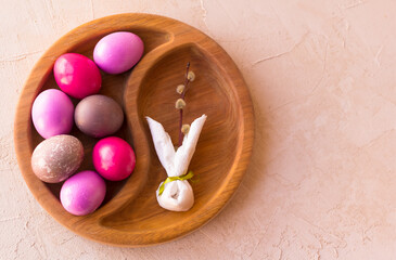 PREPARATIONS FOR EASTER. A WOODEN TRAY WITH PAINTED EGGS AND A PAPER RABBIT. copy space