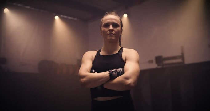 A Portrait Of A Strong Kickboxing Woman In An MMA Gym. Shot In A Crossfit Boxing Gym With Low Key Lighting And A Scattering Of Haze. Captured On Red Digital Cinema Camera 