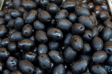 Black olives close up on market, food background