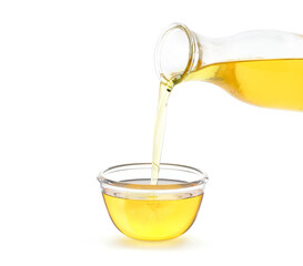 Pouring cooking oil from bottle into glass bowl isolated on white background.
