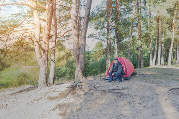 Man sitting in the forest near the tent.