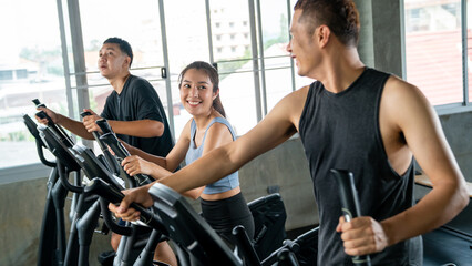 Healthy Asian athletic man and woman in sportswear workout exercise on cycling machine together at...