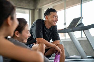 Fototapeta premium Healthy Asian athletic man and woman in sportswear relaxing cool down after do workout exercise at fitness gym. Male and female do sport training together at sport club. Health care motivation concept