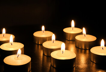 pointLots of candles on a wooden tablefocusspot specifically in on a black background.
