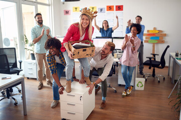 A group of employees is having fun while giving a ride to their female colleague through the office. Employees, job, office