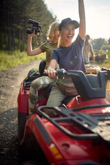 Young girls enjoy riding the quad in the nature. Riding, nature, friendship, together