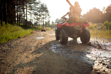 Young people on an off road adventure. Man driving quad with girlfriend sitting behind him, and enjoying the ride in mountains forest. Nature outdoors. Sport, freedom, holiday concept. © luckybusiness