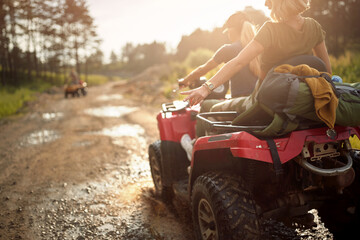 Young girls ride quads on a muddy road in the nature. Riding, nature, friendship, together