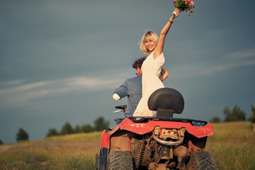 Joyful bride with bridal bouquet. Newlywed couple riding quad. Love, wedding, happiness, couple concept. © luckybusiness
