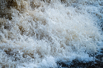 Fototapeta na wymiar close up of flowing water, rapid water splashes of an white water river or stream, bubbly water