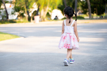 Rear back view beautiful kid girl jogging in public park in evening time. Summer or spring time. Relaxing child wearing face mask for protect spread virus and air pollution PM2.5. Children 5 year old.