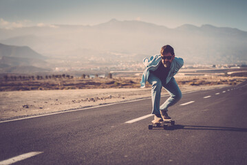 Adult youth man go speed on longboard skate on asphalt road. Mature people enjoy outdoor leisure activity. Freedom and youthful lifestyle concept. Enjoying life and scenic place - obrazy, fototapety, plakaty