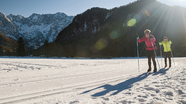 Recreational couple cross country skiing on a beautiful snow track in the mountain foothill on a sunny winter day.