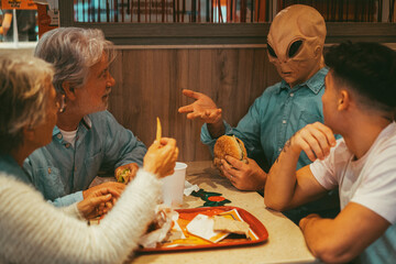 Happy family with ufo alien estraterrestrial guest enjoy together hamburgers in fast food. Concept...