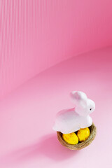 Easter eggs and rabbit on a pink background. Yellow-golden eggs in a nest. Easter concept. Copy space